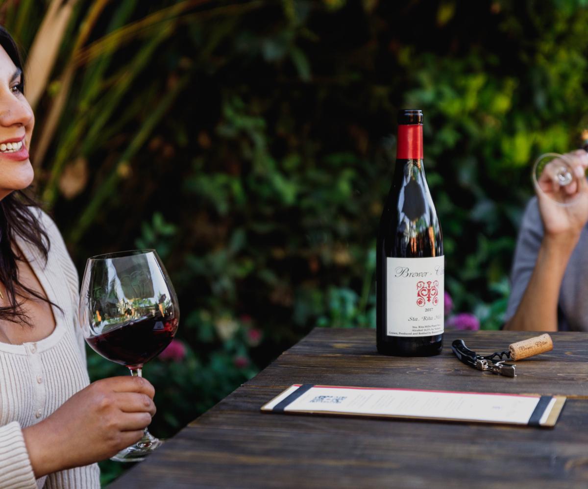 Two women enjoying glasses of Brewer-Clifton wine at Los Olivos tasting room